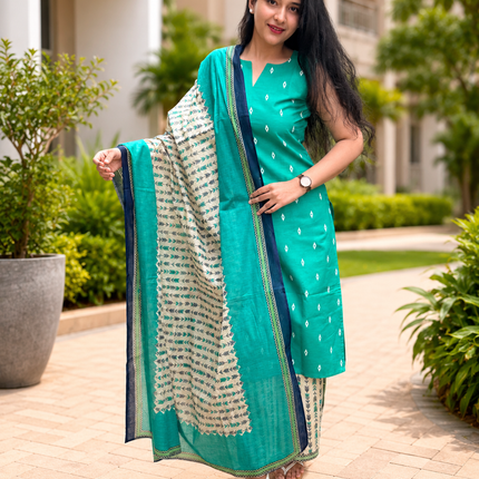 Woman in a teal traditional outfit with a patterned dupatta standing outdoors.