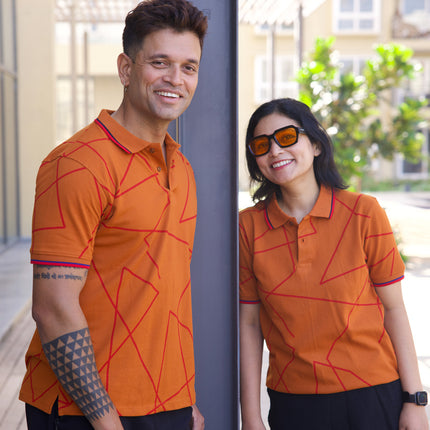 Two people wearing matching orange polo shirts with geometric patterns outdoors.