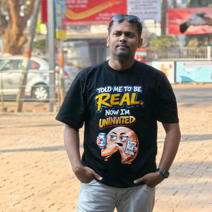 Man wearing RREFLEKT black t-shirt with humorous text and graphics on a street background