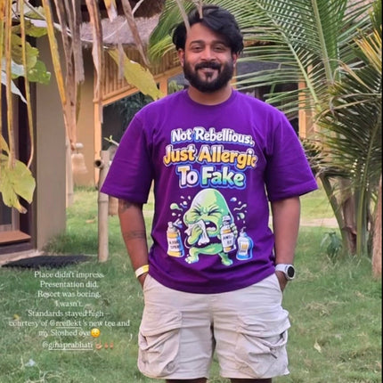 Man wearing RREFLEKT purple t-shirt with a graphic design in a tropical setting