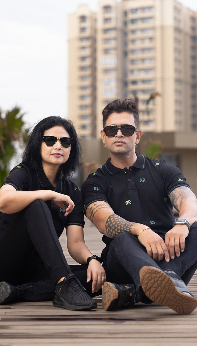 Two people sitting on a wooden deck with buildings in the background