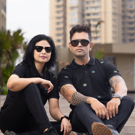 Two people sitting on a wooden deck with buildings in the background