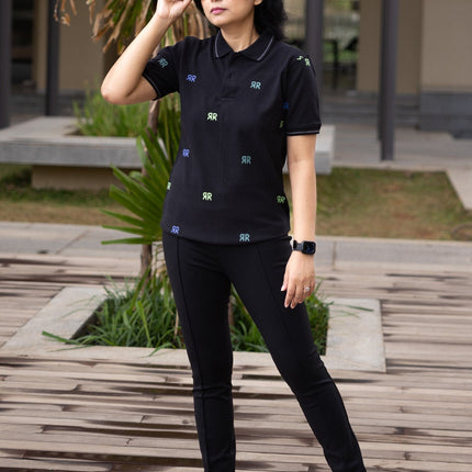Person wearing a black outfit with sunglasses outdoors on a wooden deck.