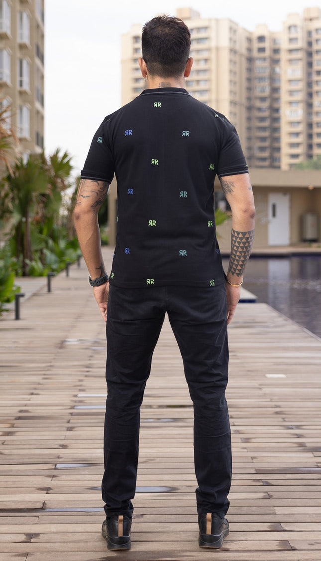 Man standing on a wooden pathway with buildings and greenery in the background