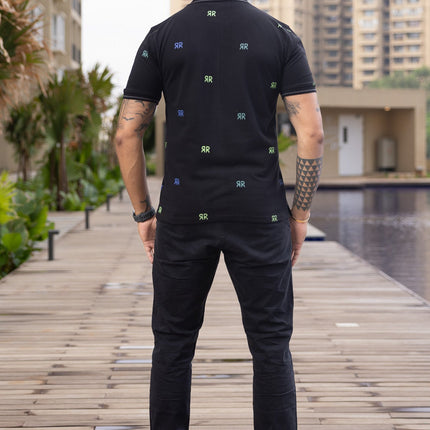 Man standing on a wooden pathway with buildings and greenery in the background