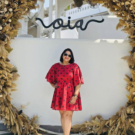 Woman in a RREFLEKT red dress standing in front of a decorative arch