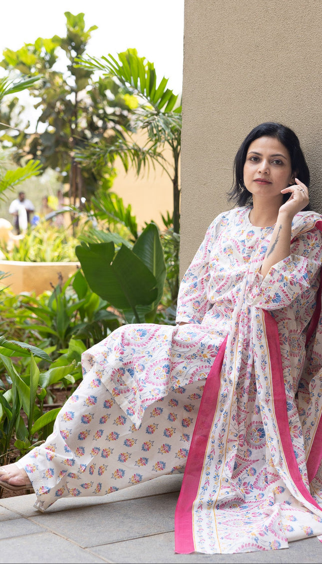 Woman in a floral dress sitting outdoors with greenery in the background