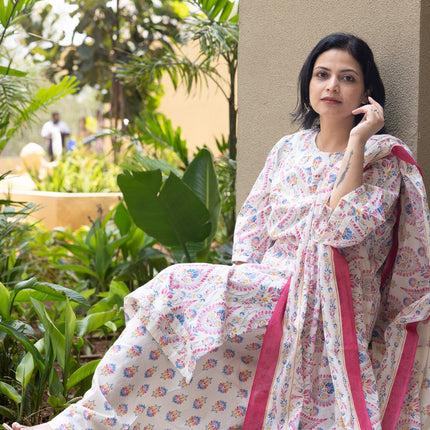 Woman in a floral dress sitting outdoors with greenery in the background
