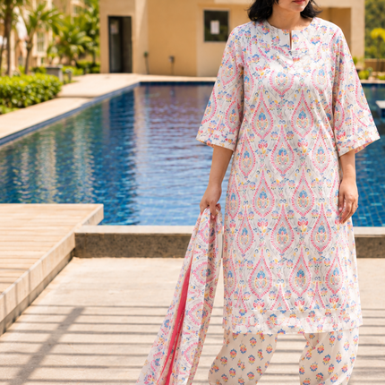 Woman in a patterned outfit standing by a pool with buildings in the background