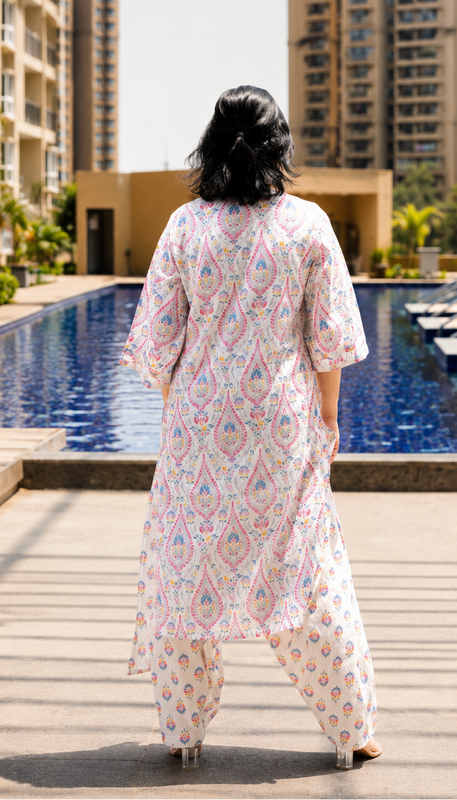 Woman in a patterned outfit standing by a pool with buildings in the background