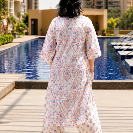 Woman in a patterned outfit standing by a pool with buildings in the background