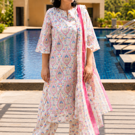 Woman in a floral outfit standing by a pool with buildings in the background