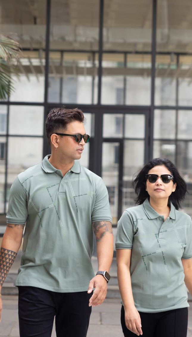 Two people wearing matching green polo shirts walking outdoors.