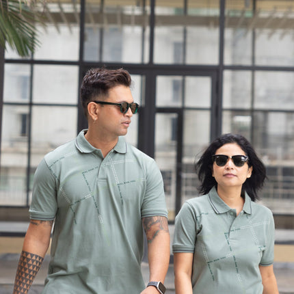 Two people wearing matching green polo shirts walking outdoors.