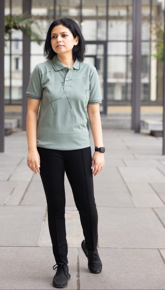 Woman wearing a green polo shirt and black pants standing in an outdoor setting.