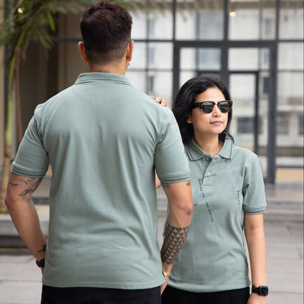 Two people wearing matching green polo shirts outdoors.