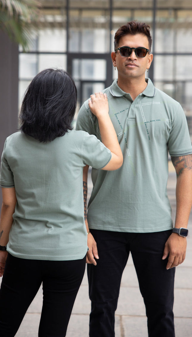 Two people wearing matching green polo shirts outdoors.