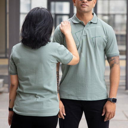 Two people wearing matching green polo shirts outdoors.