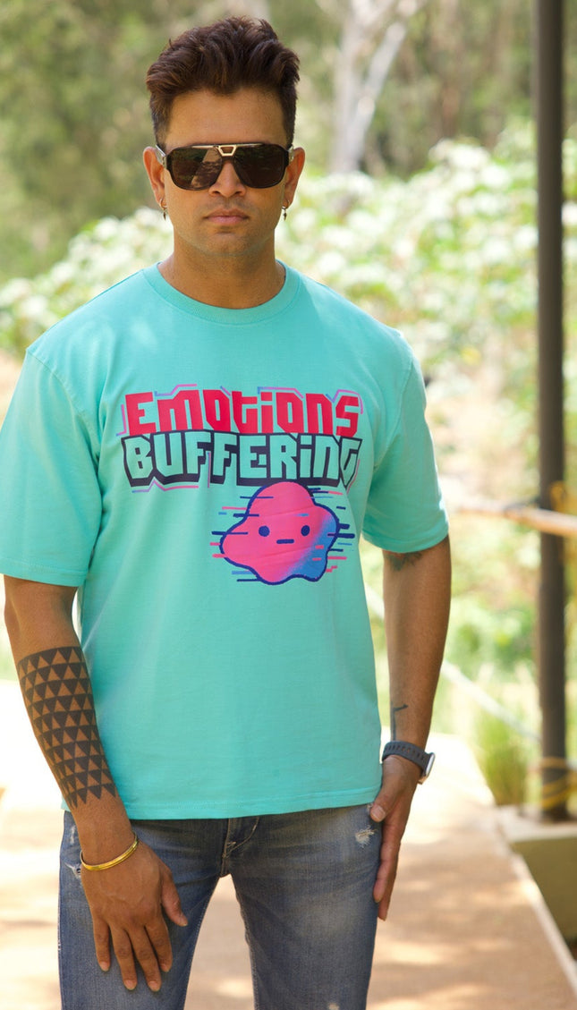 Person wearing a teal t-shirt with 'Emotions Buffering' graphic outdoors.