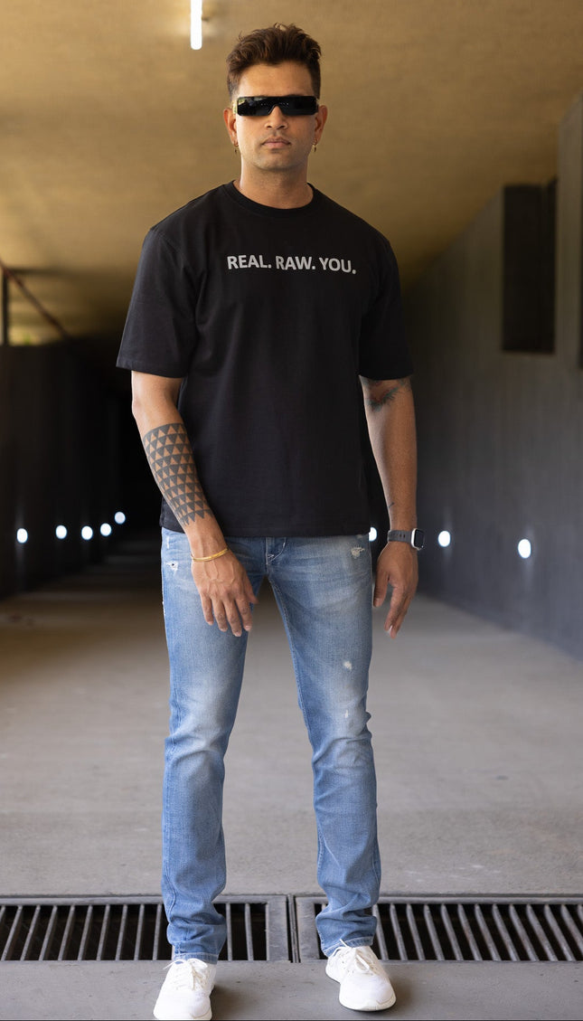 Man wearing a black t-shirt with text and sunglasses in an indoor setting