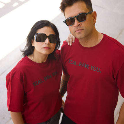 Two people wearing red t-shirts with text, standing close together indoors.