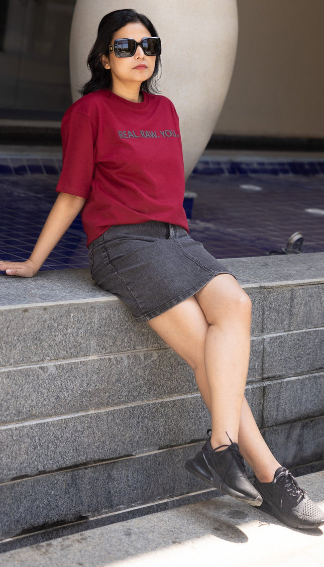 Woman sitting by a pool wearing sunglasses and casual clothing.
