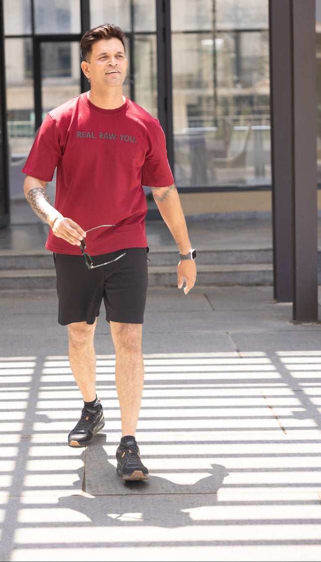 Man in red shirt and black shorts walking on a crosswalk with a blurred background