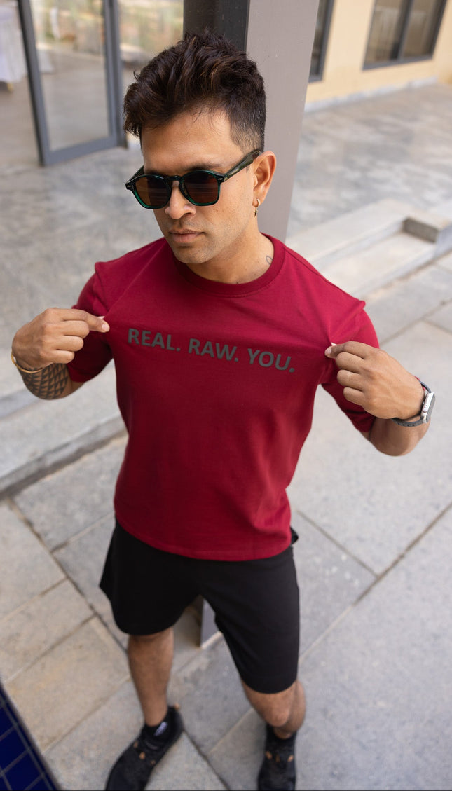 Man wearing a red t-shirt with text, standing outdoors.