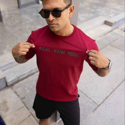Man wearing a red t-shirt with text, standing outdoors.