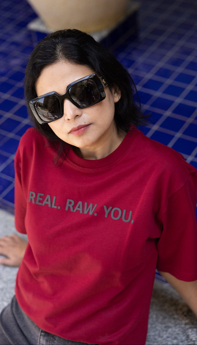 Person wearing a red t-shirt with text, standing by a poolside.