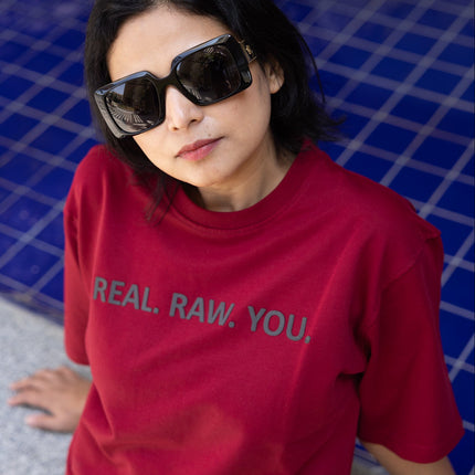Person wearing a red t-shirt with text, standing by a poolside.