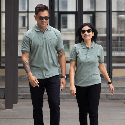 Two people wearing matching green shirts and black pants walking outdoors.